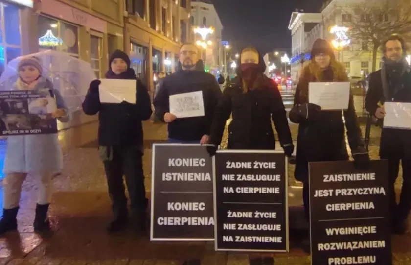 Protest in Poland at night: activists on a city street with signs such as "Koniec istnienia, koniec cierpienia" (end of existence, end of suffering)